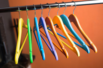 Wooden coat hangers on clothes rail and orange background