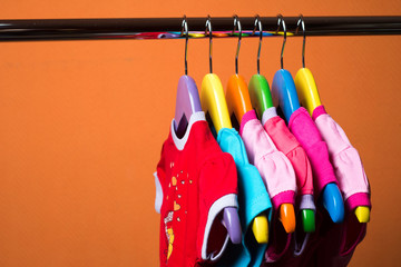 Hangers with colourful clothes on orange background