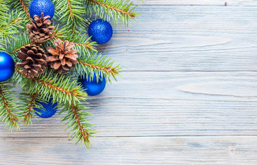 Ветки ели с синими шариками и шишками на деревянном фоне. Новогодний фон. Рождество. Новый год.