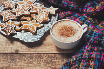 Gingerbread with cup of coffee and warm scarf on wooden background