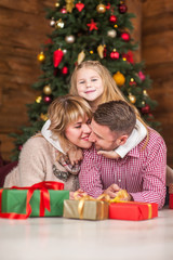 Fototapeta na wymiar .Family of mother, father and little child daughter near Christmas tree with presents, decorations and New Year or Christmas