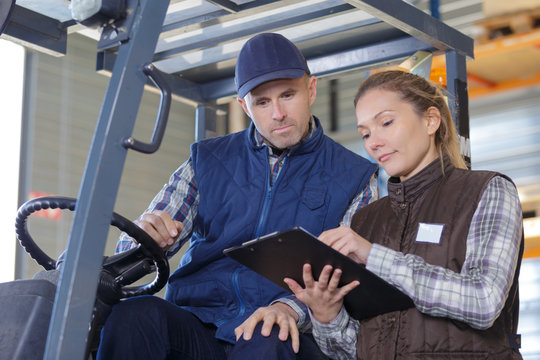 warehouse manager talking with forklift driver in a large warehouse