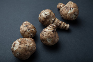 The tubers of raw Jerusalem artichoke are isolated on a black background.