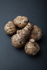 The tubers of the organic topinambur (Jerusalem artichoke) on black background.