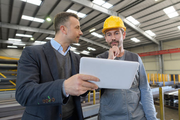 metal worker in workshop using digital tablet