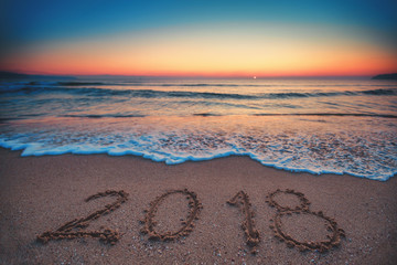 Happy New Year 2018 concept, lettering on the beach. Sea sunrise