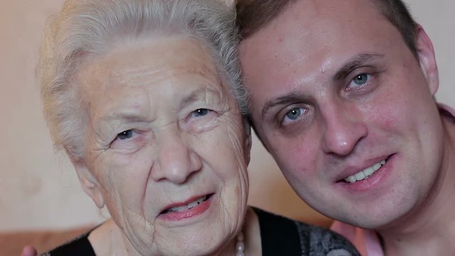 Grandson and grandmother together looking at the camera. Old age and youth
