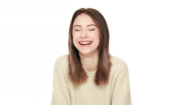 Horizontal closeup portrait of optimistic woman with caucasian appearance laughing out loud joking and feeling joy while posing over white background. Concept of emotions