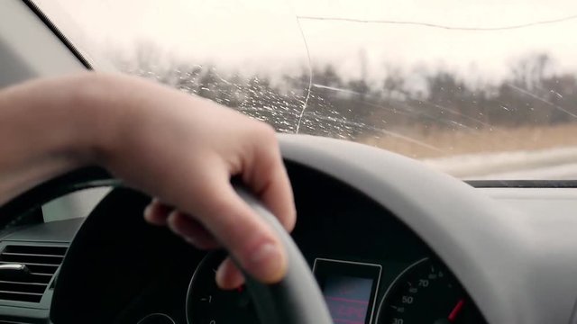 Man's hands holding steering wheel of car