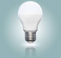 Lit LED light bulb isolated on a blue green gradient background, closeup