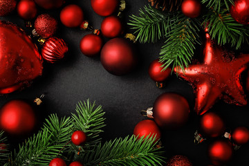 red christmas ornaments and fir tree branches on black background