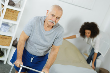 Fototapeta premium senior man with walker at home with home help woman