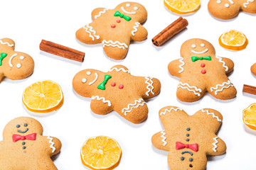 Christmas gingerbread men with lemon and cinnamon sticks on white background. A symbol of winter and new year holidays.