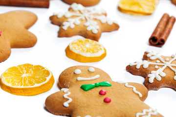 Fototapeta premium Christmas gingerbread men and snowflakes with lemon and cinnamon sticks on white background. A symbol of winter and new year holidays.