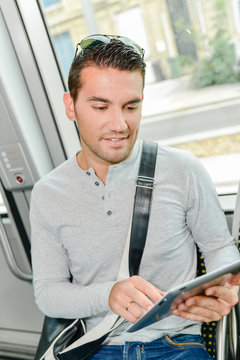 man using his tablet inside a public transport