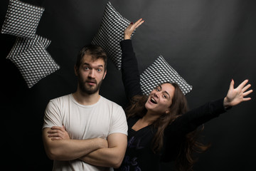 cheerful young people throwing pillows on a black background. young cheerful couple.