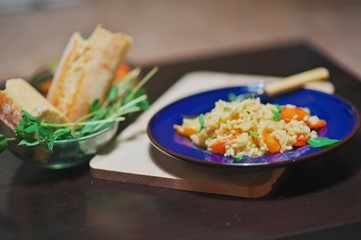 Diet of rice pilaf with apricots, mint leaves, on a dark blue plate on the black table, top view.