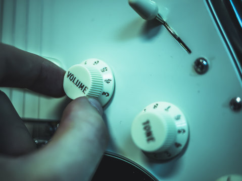macro shot of man changing volume on the electronic guitar