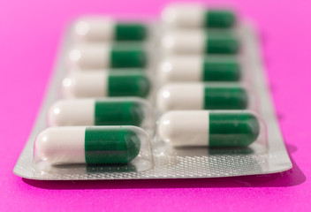 Front view of white and green capsules on medicine box.