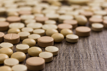 Obraz na płótnie Canvas Heap of assorted beige capsules on wooden table.