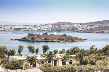 View over a bay with an island and a typical village on Paros, one of the Cyclade islands in...