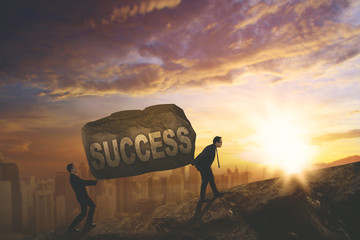 Two young businessmen lifting success word © Creativa Images
