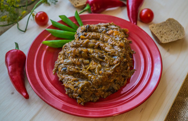 Stewed forest mushrooms cooked with onions and carrots on a red plate with bread and chili