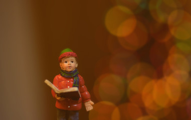 close up statue of little boy reading bible and round light bokeh for Christmas background, filtered tones