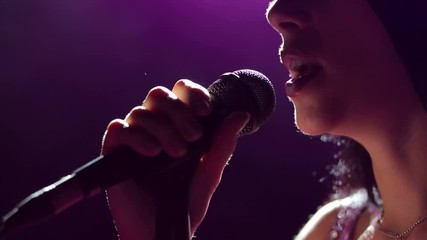 Close-up of the face of the singer with microphone on a black smoky background. The singer sings a song on stage in the dark, smoke, purple light, concert. - Powered by Adobe