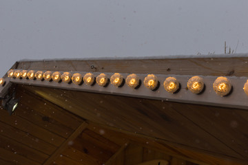 snowfall on christmas market with lights lamps and decoration in advent december