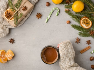 Winter hot drink female hands in a sweater holding a Cup of hot chocolate on a gray concrete background tangerines scenery