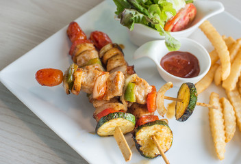 Tasty delicious pork/chicken skewer sticks - grilled pork/chicken kebab with red and green pepper with french fried and vegetable salad on whith plate