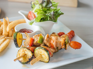 Tasty delicious pork/chicken skewer sticks - grilled pork/chicken kebab with red and green pepper with french fried and vegetable salad on whith plate