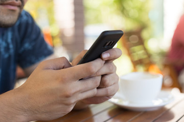 Closeup of people hand using smart phone at coffee shop