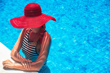 Beautiful european woman in red hat is relaxing in the swimming pool