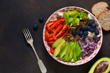 Healthy vegetarian lunch plate with avocado, lettuce, pepper, blueberries and with flax seeds.