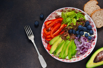 Healthy vegetarian lunch plate with avocado, lettuce, pepper, blueberries and with flax seeds.