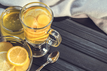 Tea with ginger and lemon in a glass cup and yellow sweets on a wooden background