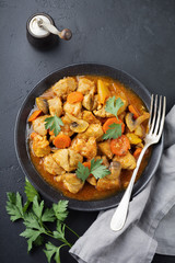 Goulash traditional Hungarian dish. Stew with pepper and tomato sauce in ceramic plate on dark black stone or concrete background. Selective focus. Top view.