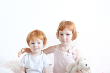 Red-haired brother and sister embrace on the white background