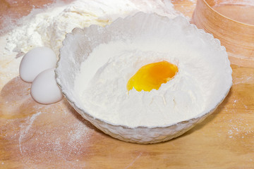Broken egg in bowl with flour and two whole eggs