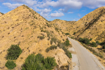 Asphalt road winds between the wilderness hills of Southern California.