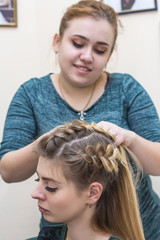 Naklejka premium A vertical crop shot of haircutting by pretty barber in a beauty salon
