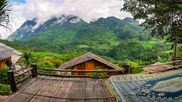 The panoramic view of forest and high mountains, which are covered with beautiful mist,  visible from the wooden terrace.of guesthouse . the roof made from grass 's leaves