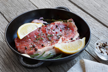 Raw beef steak with spices and herbs.