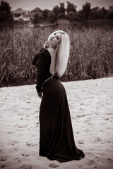 Naklejka premium Fashionable girl in a long blue dress in the evening against a background of nature. The concept of female beauty and elegance in fashion and style