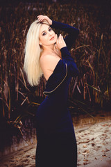 Fototapeta premium Fashionable girl in a long blue dress in the evening against a background of nature. The concept of female beauty and elegance in fashion and style