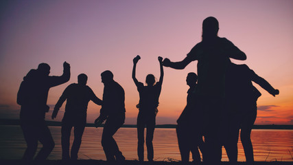 Fototapeta na wymiar Silhouette of Group young dancing people have a party at beach on sunset