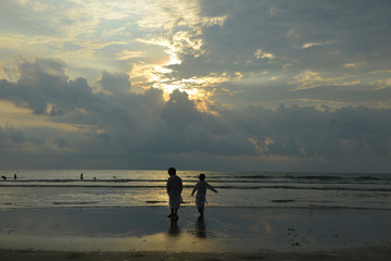 two little boys are on the beach at sunset