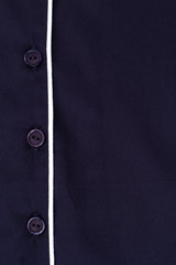 Blue shirt with white edging. Close up on button fasteners. Quality fabric and simple design.